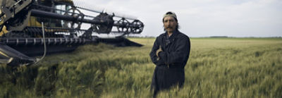 Mann auf einem Feld in der Nähe eines Mähdreschers